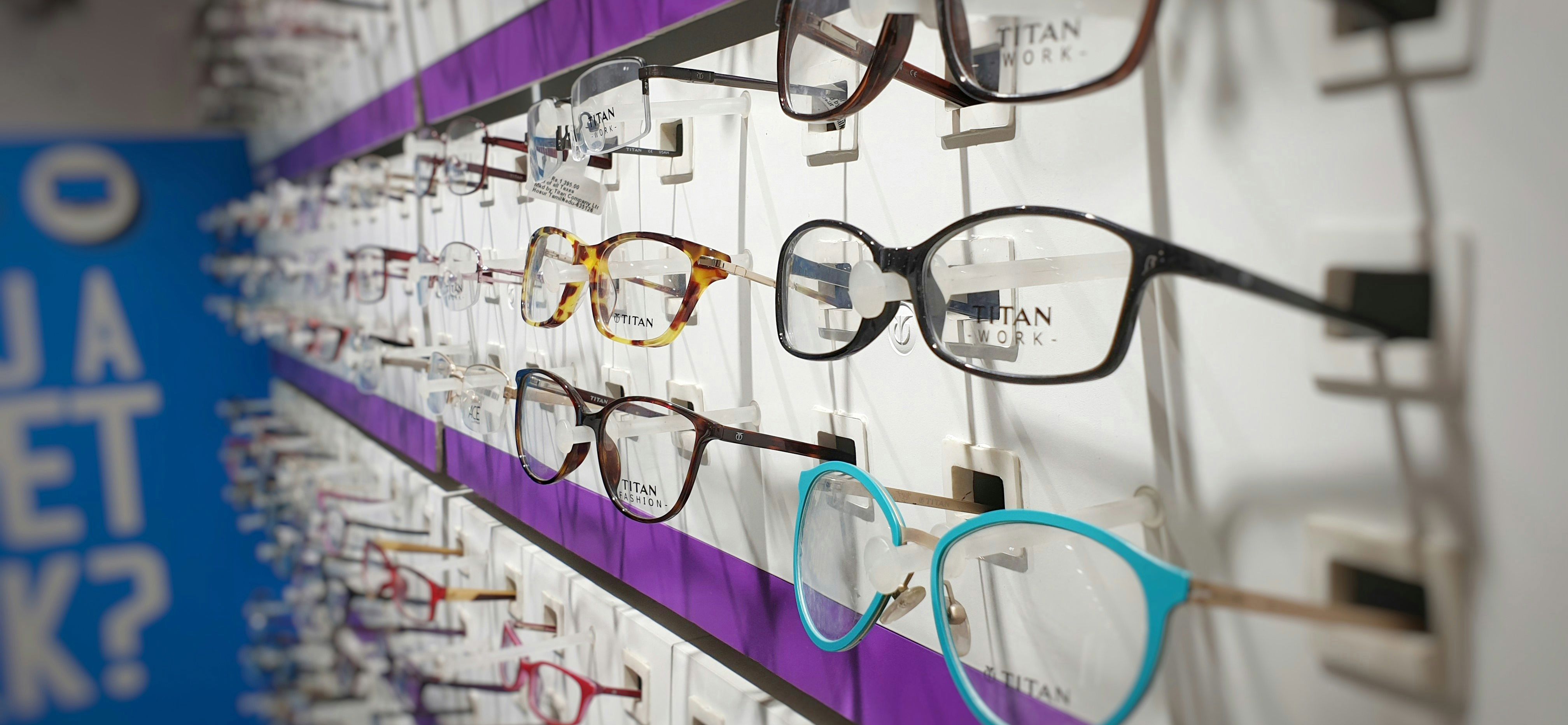 Væg med udstilling af brillestel i forskellige farver og former