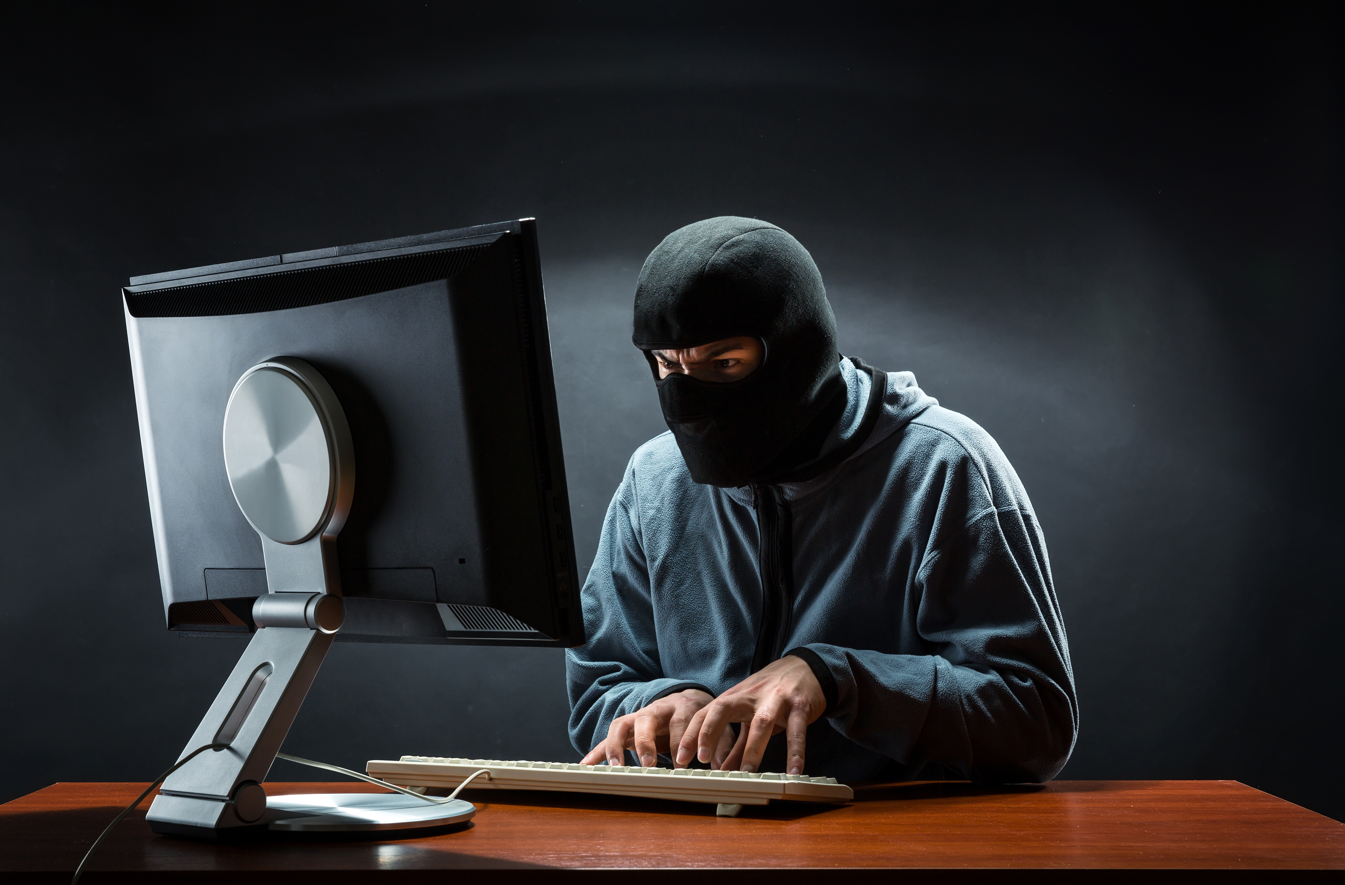 maskeret mand hacker sig ind i computer